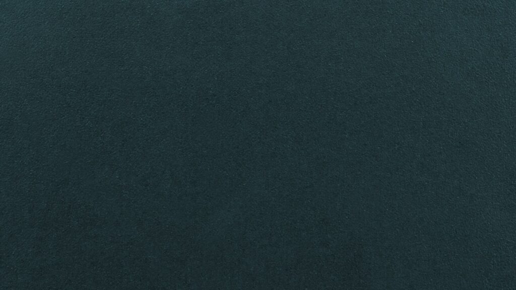 A solid, deep teal background. The surface appears smooth and uniform without any distinct patterns or textures.